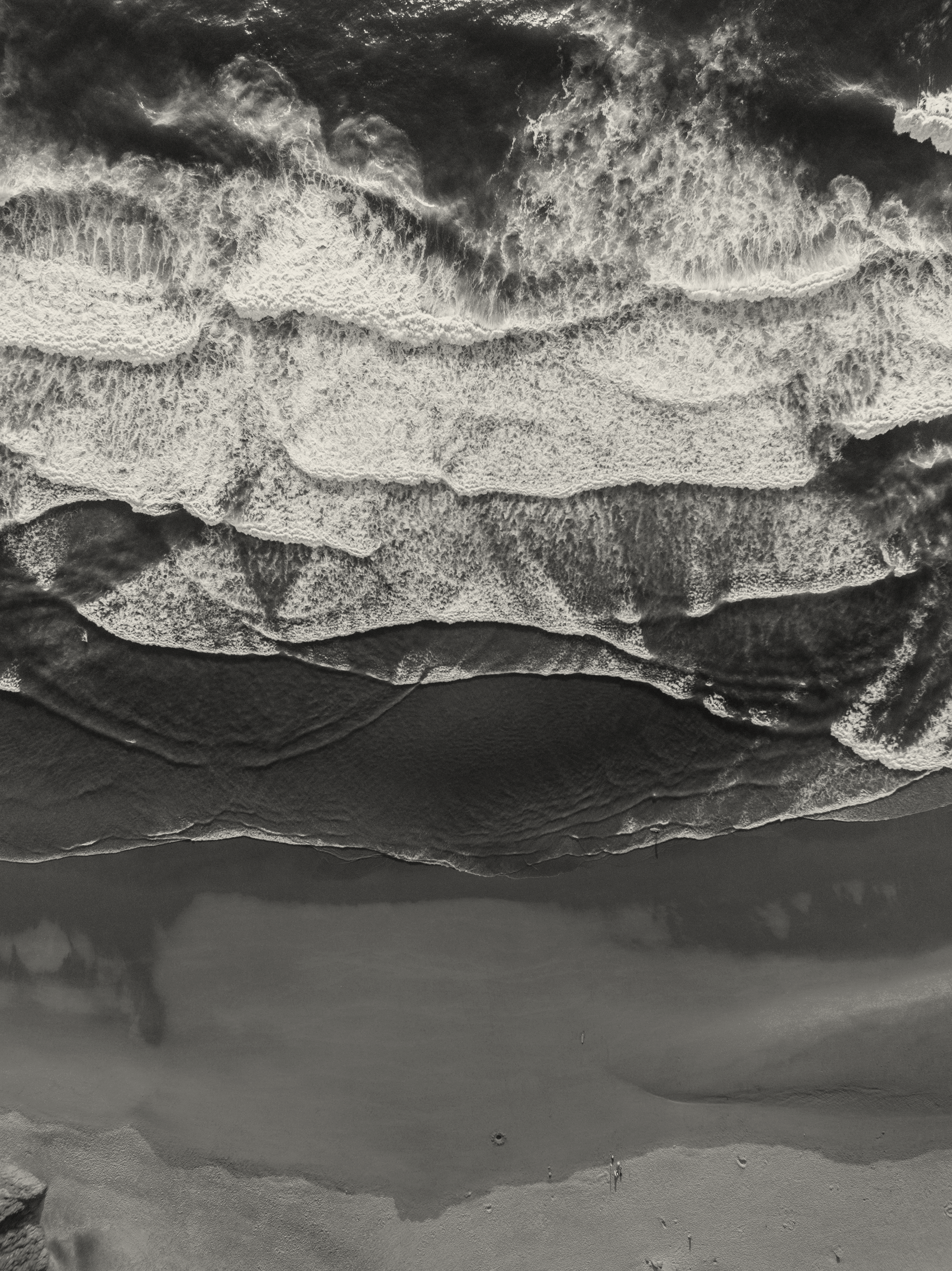 Black and white aerial view of crashing waves.